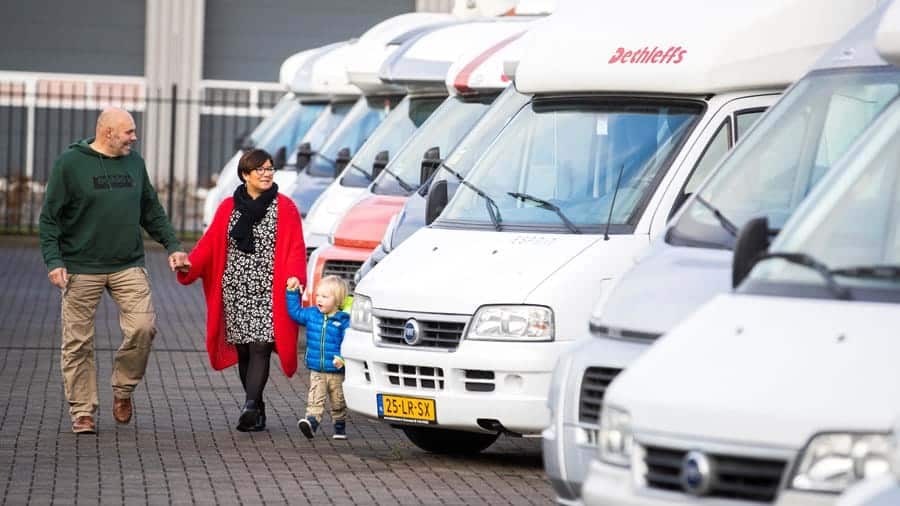 Personen bekijken een rij opgestelde campers.