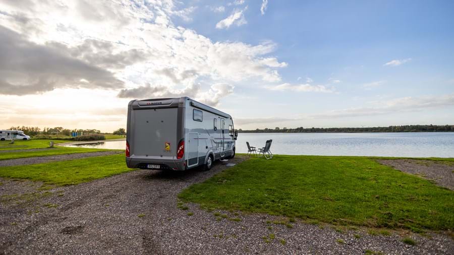 Camper aan het water bij ondergaande zon