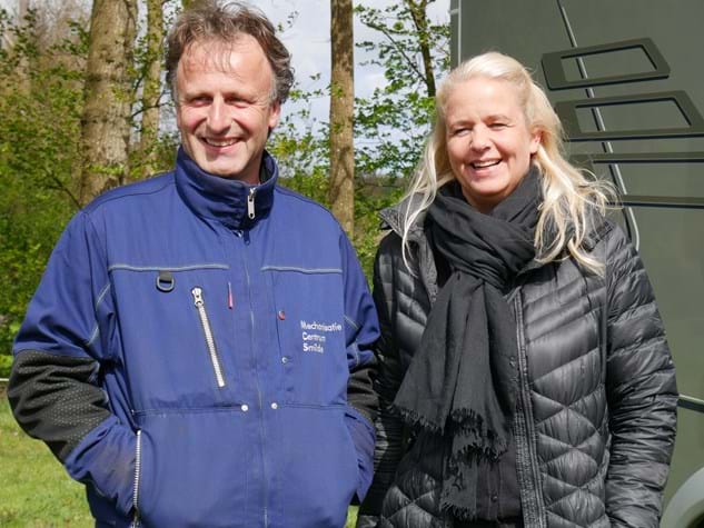 Man en vrouw staan voor camper in winterjassen