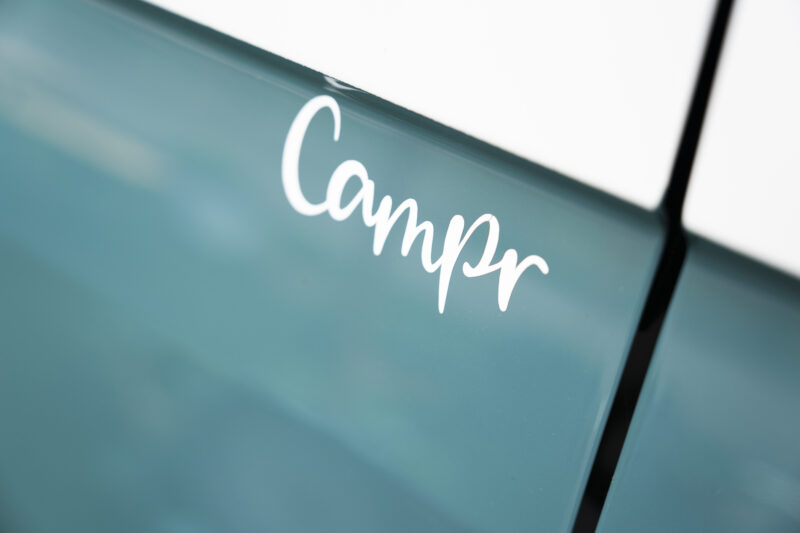 logo van Campr op de blauwe zijkant van een camper
