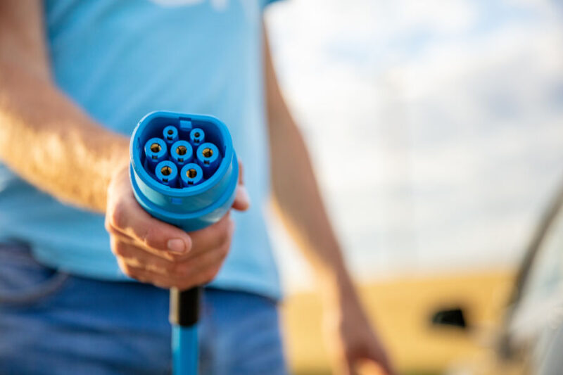 Man die een stekker voor een elektrisch voertuig vasthoudt
