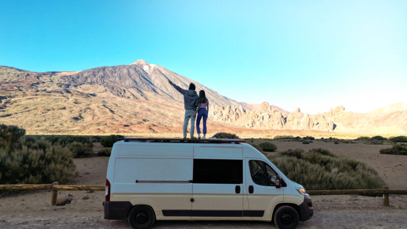 Two People Standing on Top of a Van in the Desert