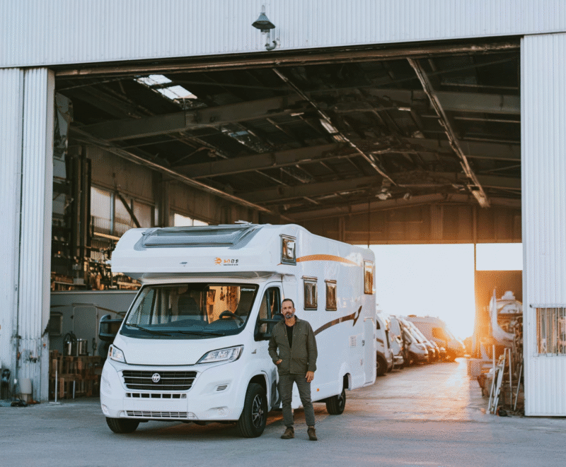 Camper in stalling met persoon naast camper