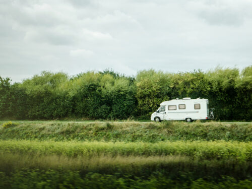 Camper rijdend over een weg met bomen
