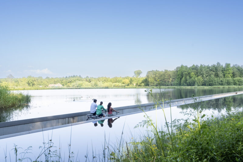 Drie personen fietsen door het water bij Bokrijk in Belgisch-Limburg
