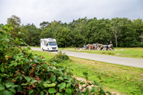 Camper rijdt op weg langs hunebedden